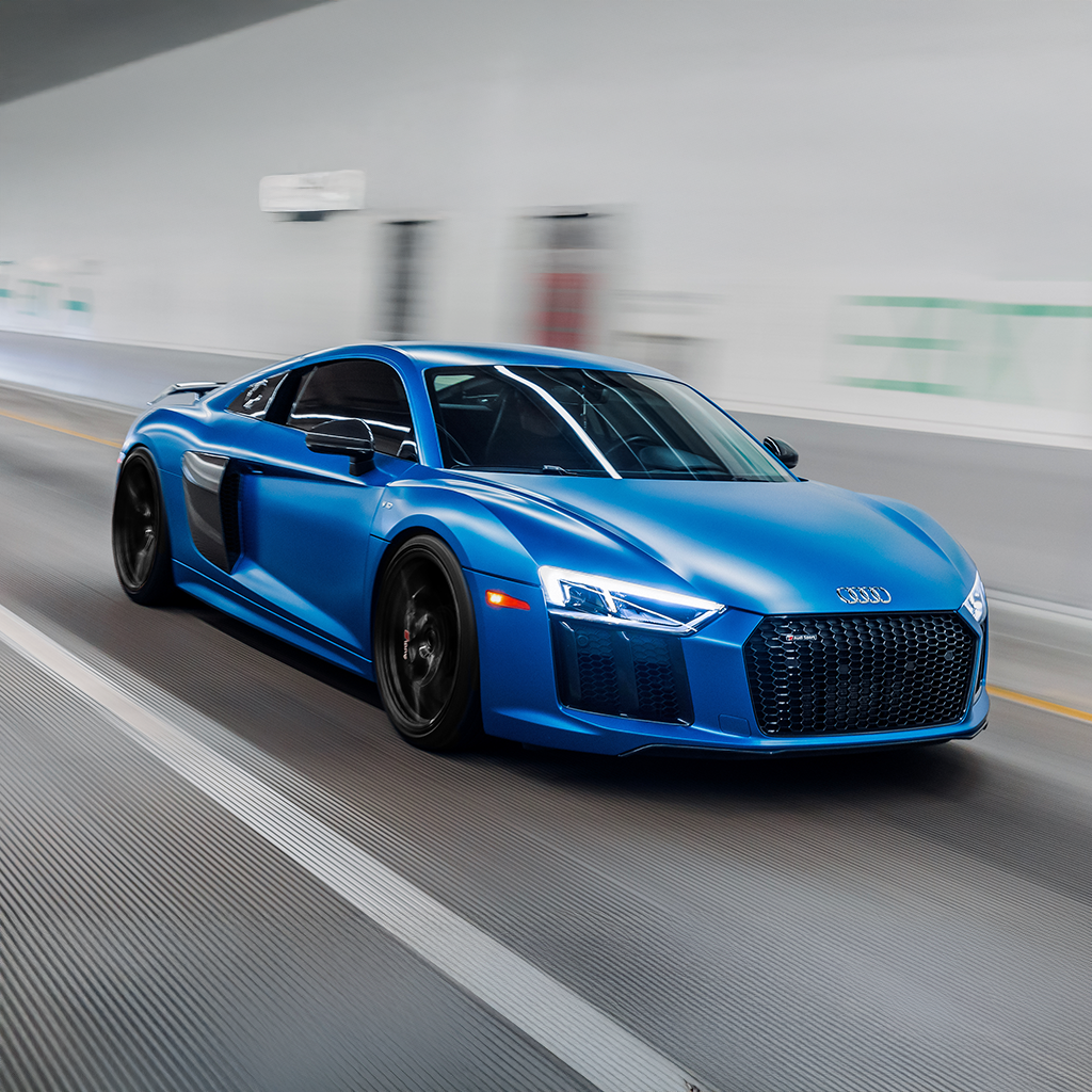 Blue Audi sports car driving on a road with a blurred background