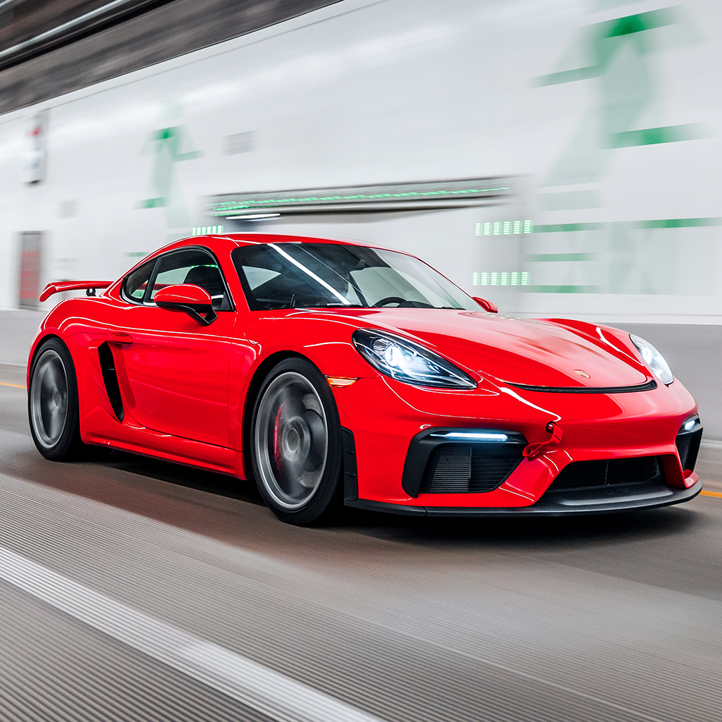 Red sports car driving on a blurred road with buildings in the background