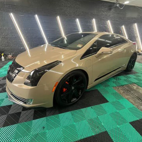 Cadillac ELR coupe wrapped in gloss desert tan vinyl with black wheels and red brake calipers, displayed under studio lighting.