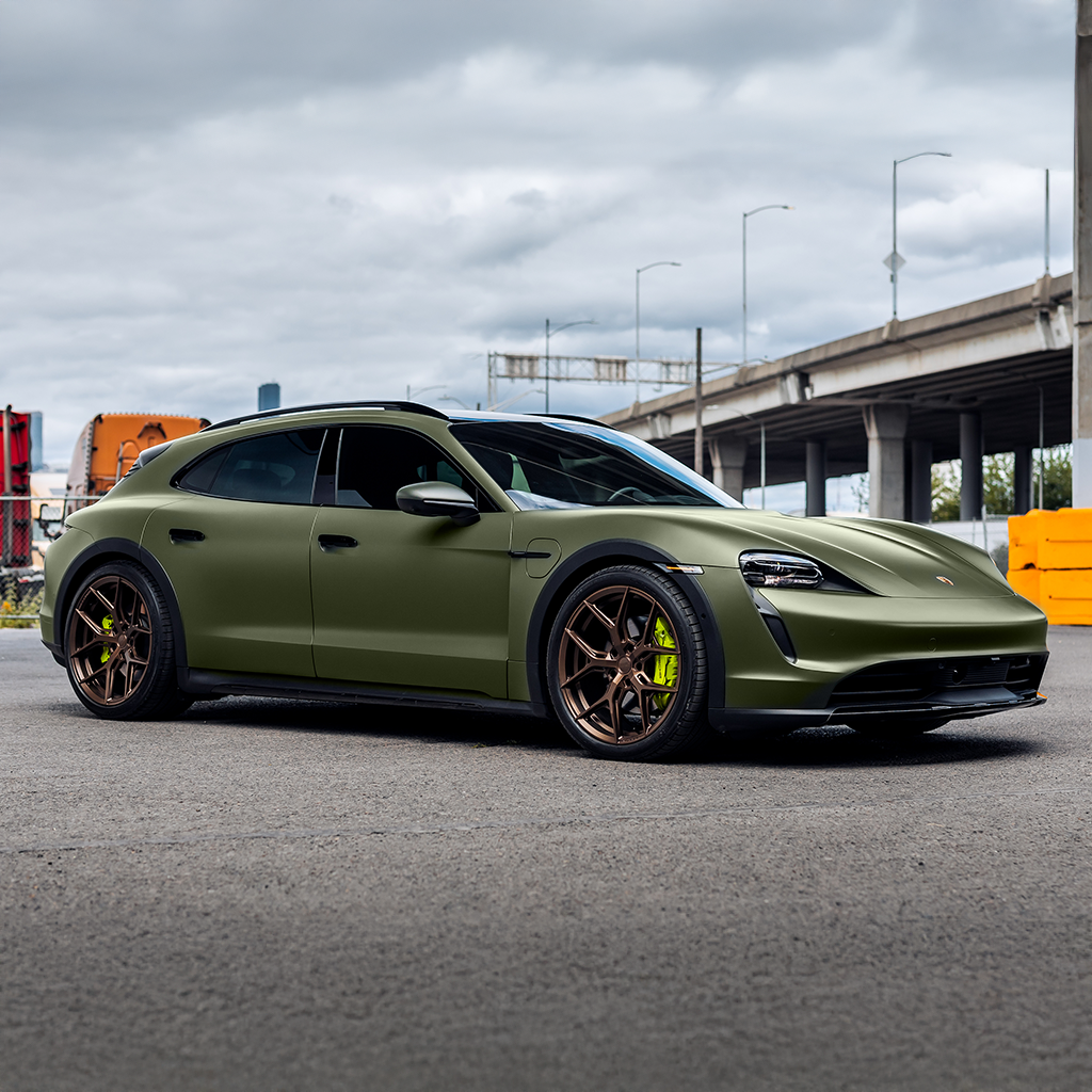 Green sports car on a road with a cloudy sky and overpass in the background