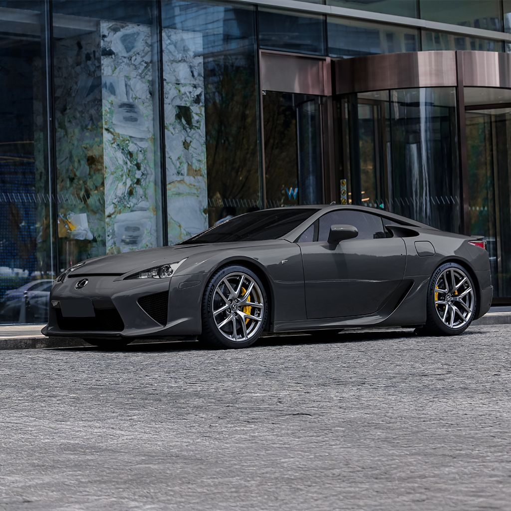 Gray sports car parked in front of a modern building entrance