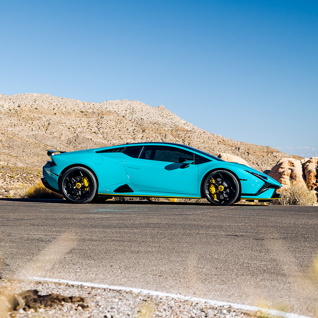 Turquoise sports car on a desert road with clear blue sky