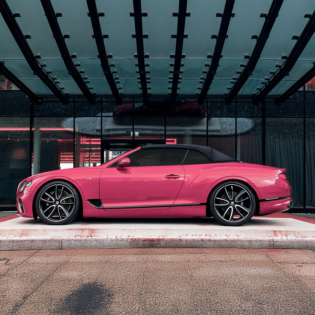 Pink convertible car parked inside a building with a modern interior.
