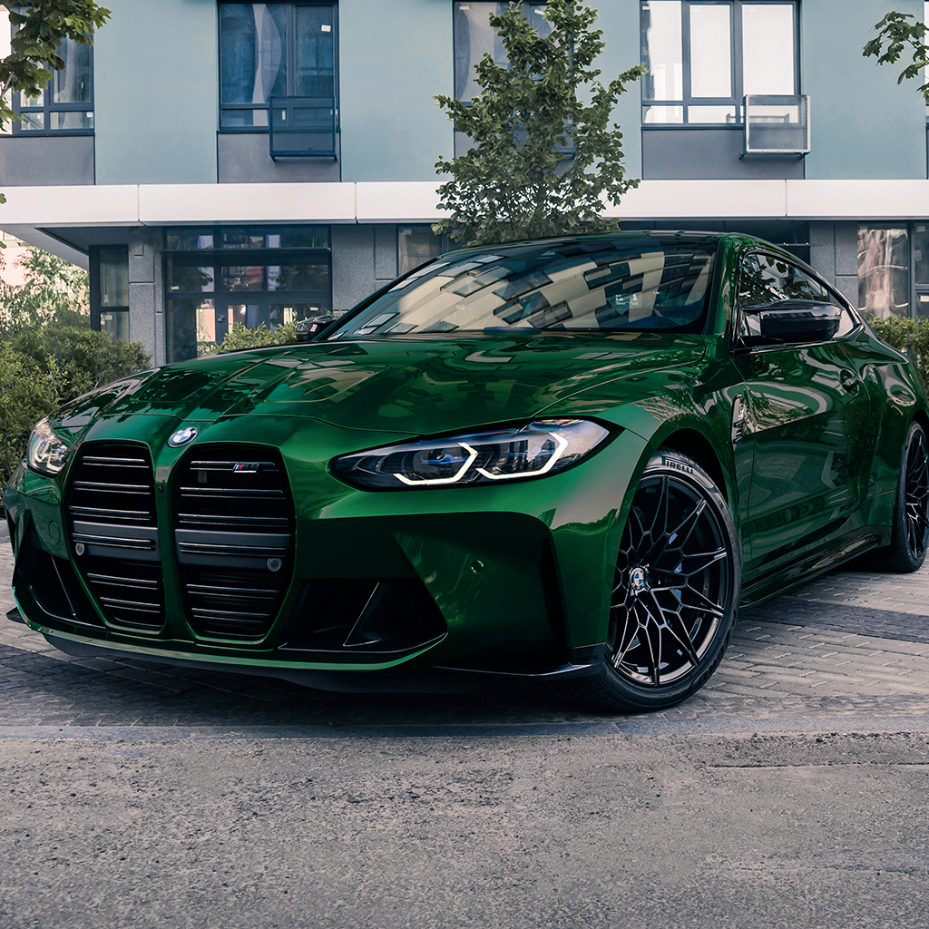 Green BMW car parked in front of a modern building