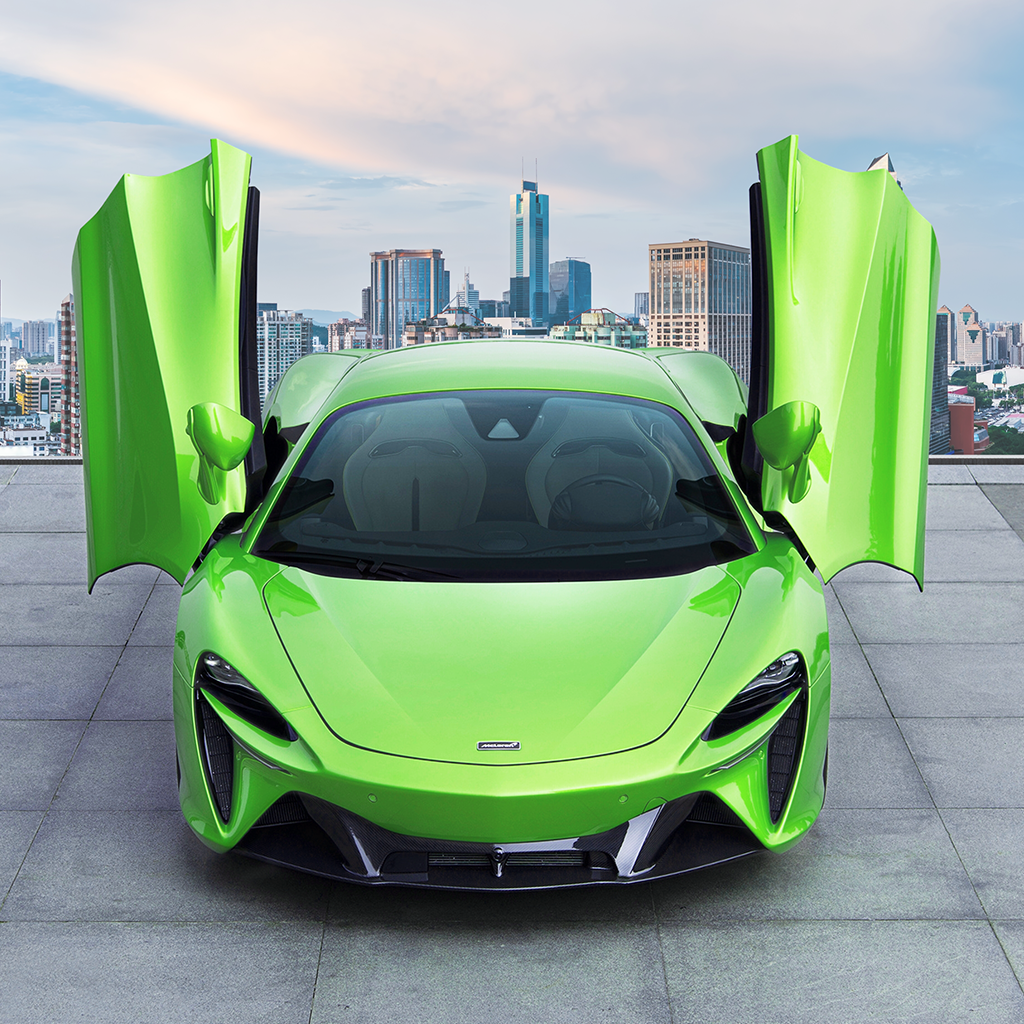 Green sports car with open doors in front of a city skyline