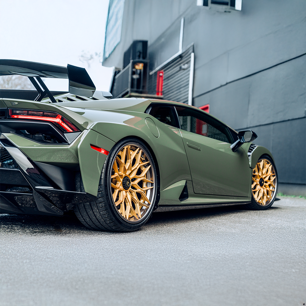 Green sports car with gold wheels parked in front of a building