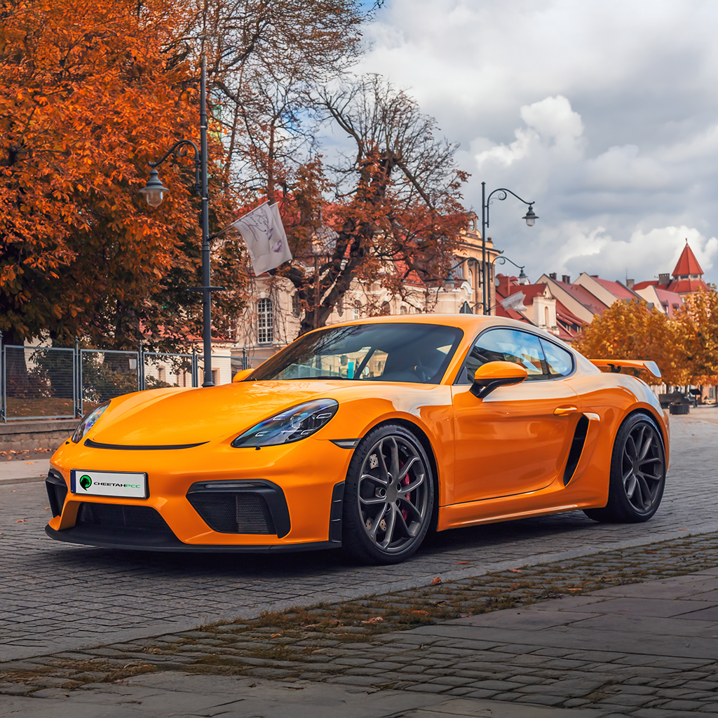 Orange sports car on a city street with autumn trees and buildings in the background