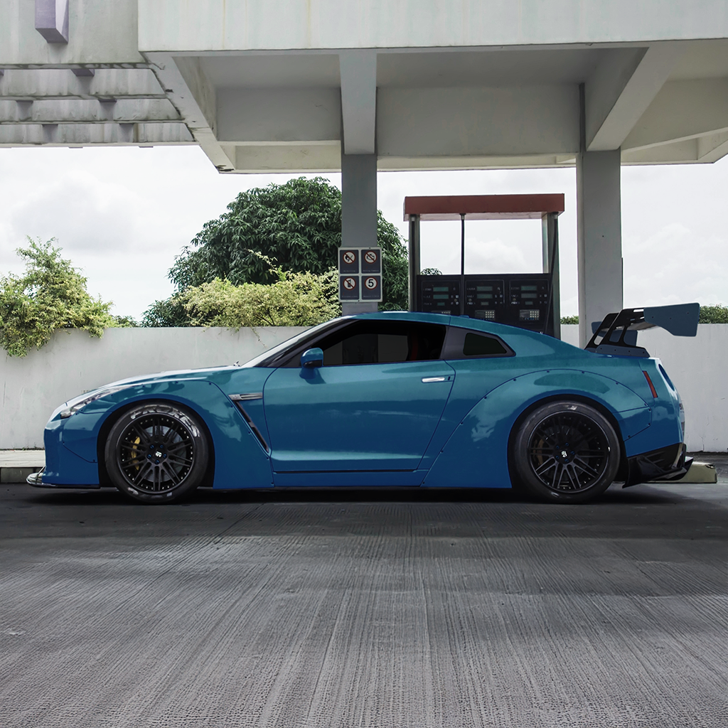 Blue sports car parked at a gas station with a modern building in the background.