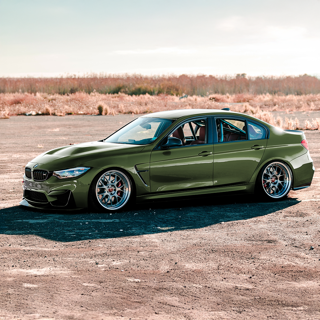 Green BMW car parked on a dirt road with a desert landscape in the background