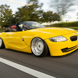 Yellow BMW convertible driving on a road with trees in the background