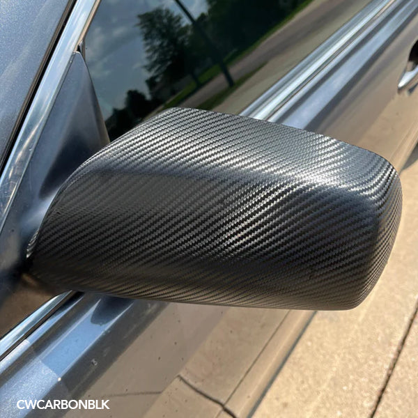 Close-up of a carbon fiber vinyl wrap on a vehicle's side mirror.