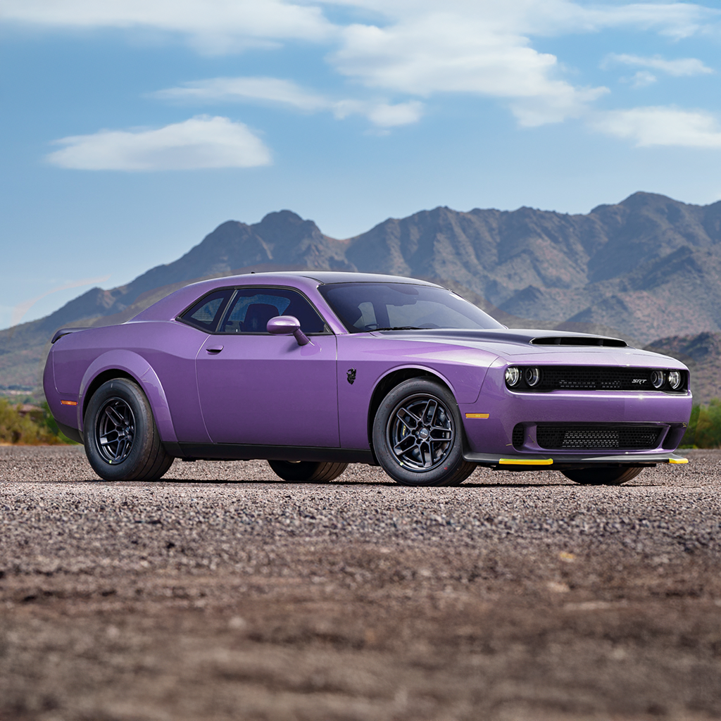 Purple muscle car on a road with mountains in the background
