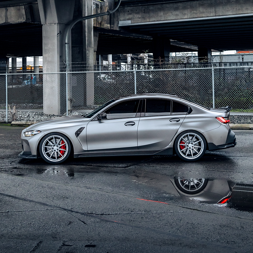 Silver car parked under a bridge with a reflective surface