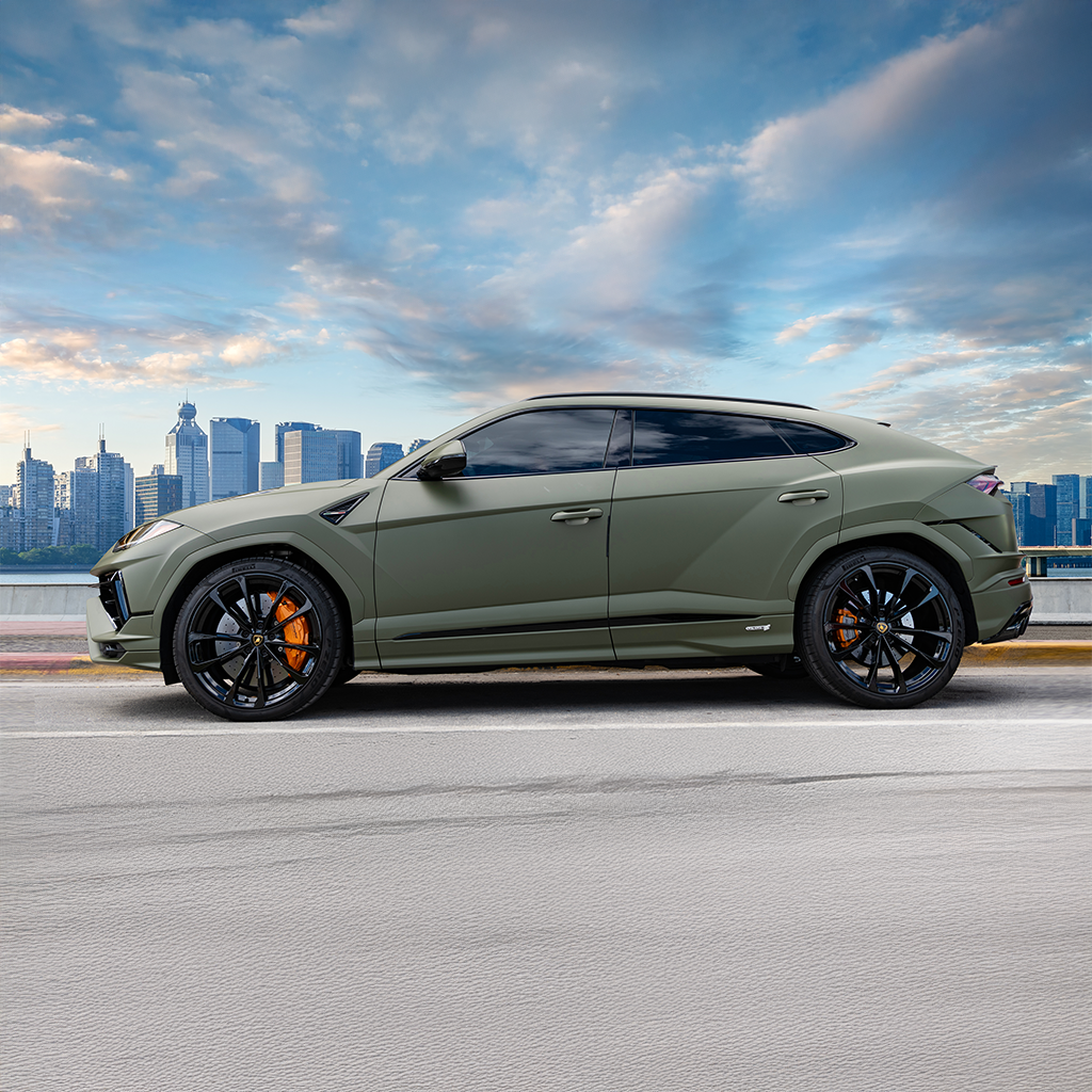 Green SUV on a road with a city skyline in the background