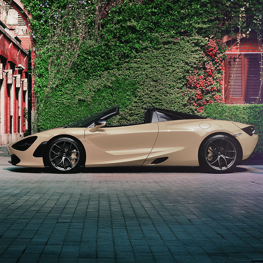 Beige convertible car parked on a brick road with greenery in the background