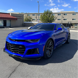 Blue Chevrolet Camaro parked on a street with buildings in the background