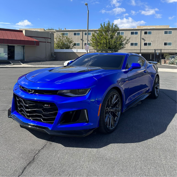 Blue Chevrolet Camaro parked on a street with buildings in the background