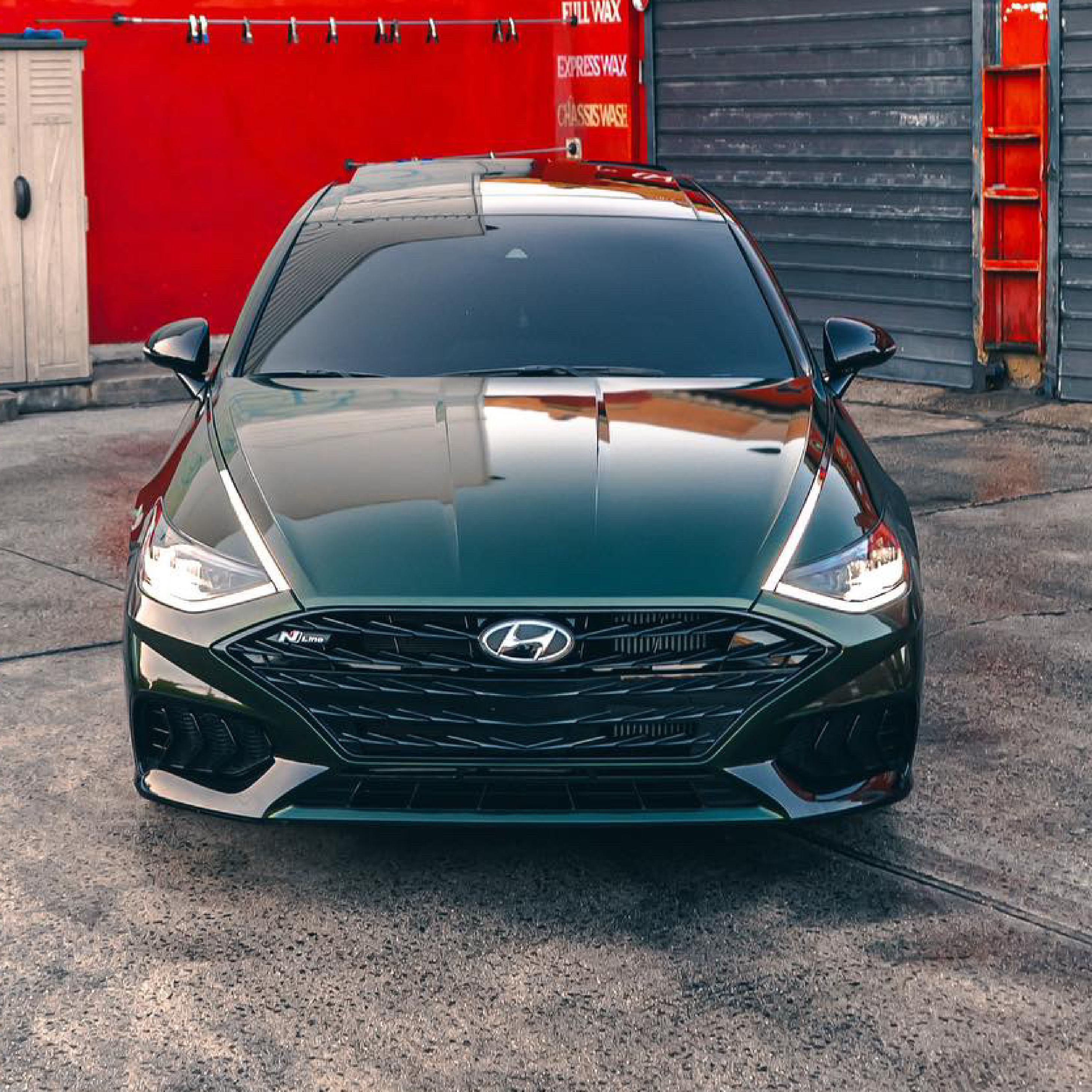 Green Hyundai car parked in front of a red building