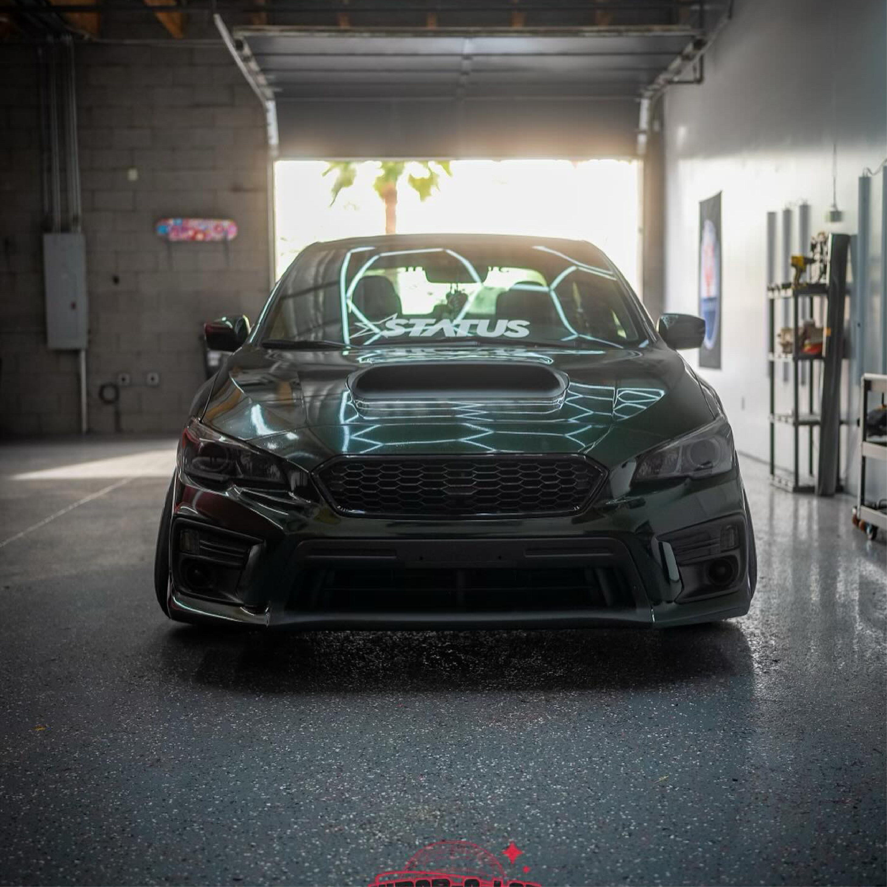 Black car with 'Status' branding in a garage