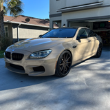 BMW sedan wrapped in gloss desert tan car wrap with black accents, parked in a residential driveway.