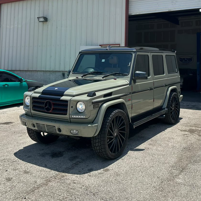 Green Mercedes-Benz G-Class SUV parked in front of a building