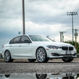White BMW car parked on a road with a cloudy sky in the background