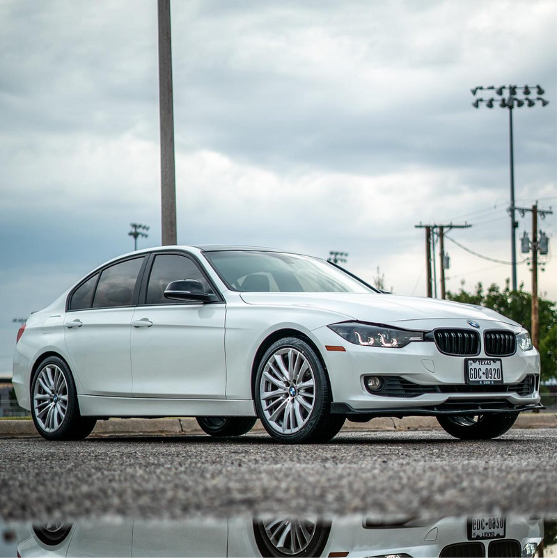 White BMW car parked on a road with a cloudy sky in the background