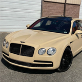 Bentley wrapped in gloss desert tan car wrap with black accents, parked in a residential driveway.