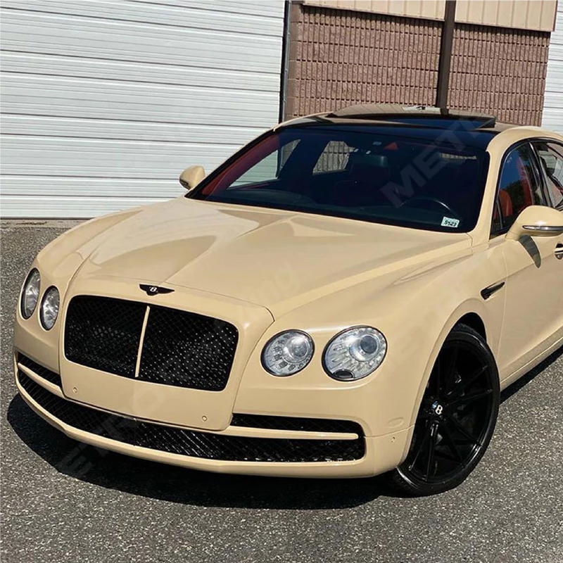 Bentley wrapped in gloss desert tan car wrap with black accents, parked in a residential driveway.