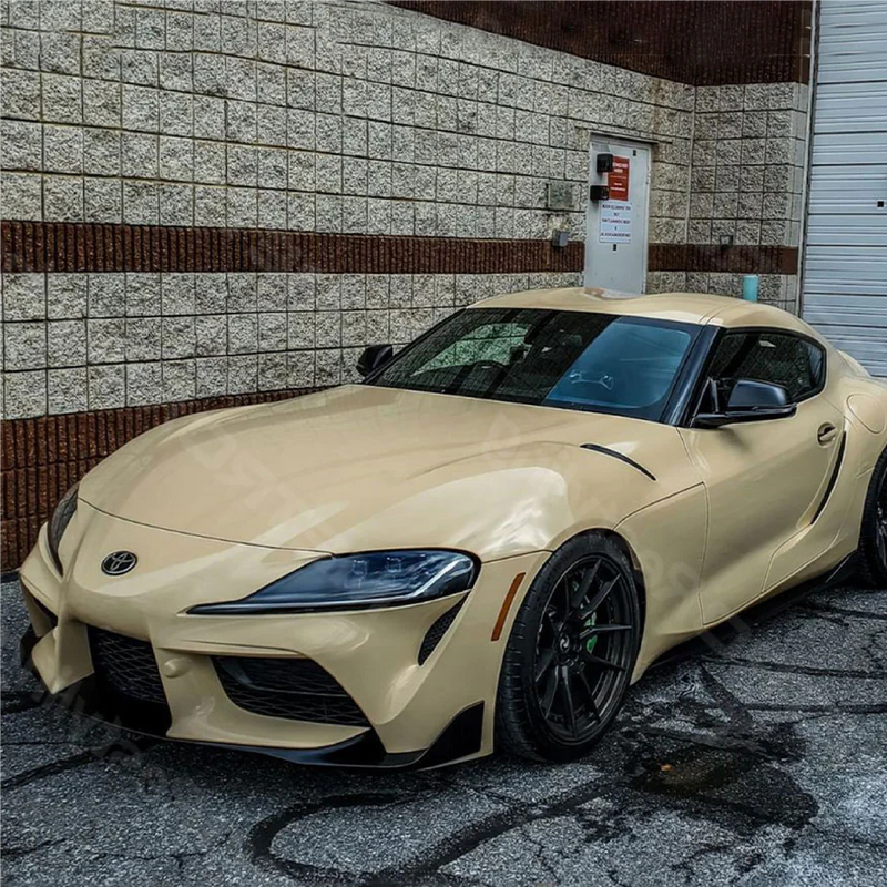 Toyota supra wrapped in gloss desert tan car wrap with black accents, parked in a residential driveway.