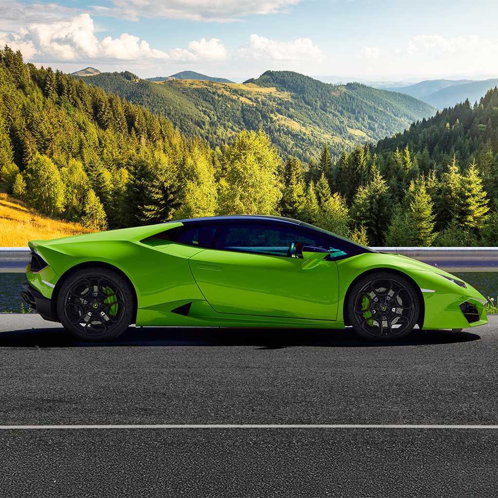 Green sports car on a road with a mountainous landscape in the background