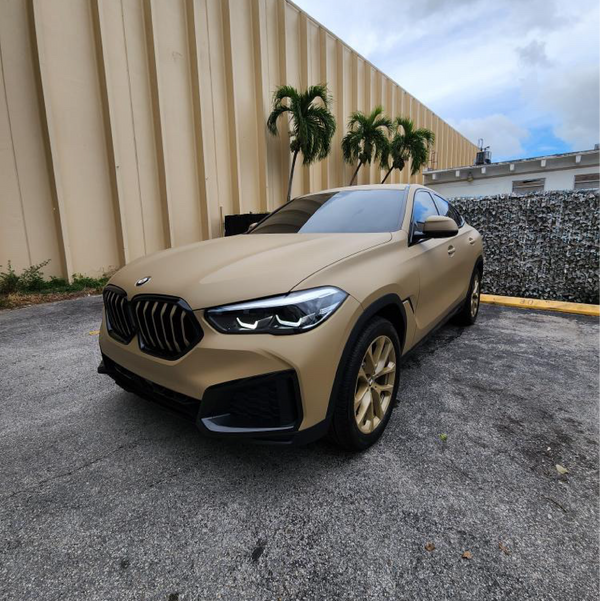 Matte Desert Tan Vinyl Car Wrap with smooth, non-glossy finish in tactical beige, shown rolled and partially unrolled for vehicle application.  
