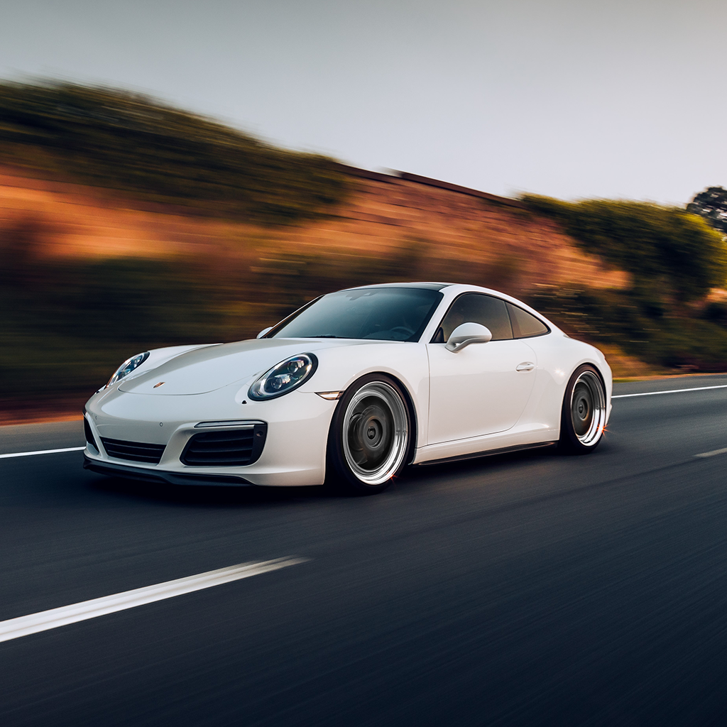 White Porsche sports car driving on a road with blurred background