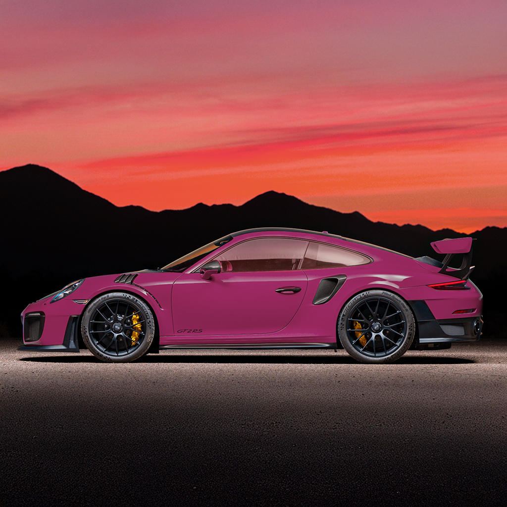 Pink sports car on a road with a mountainous landscape and sunset sky