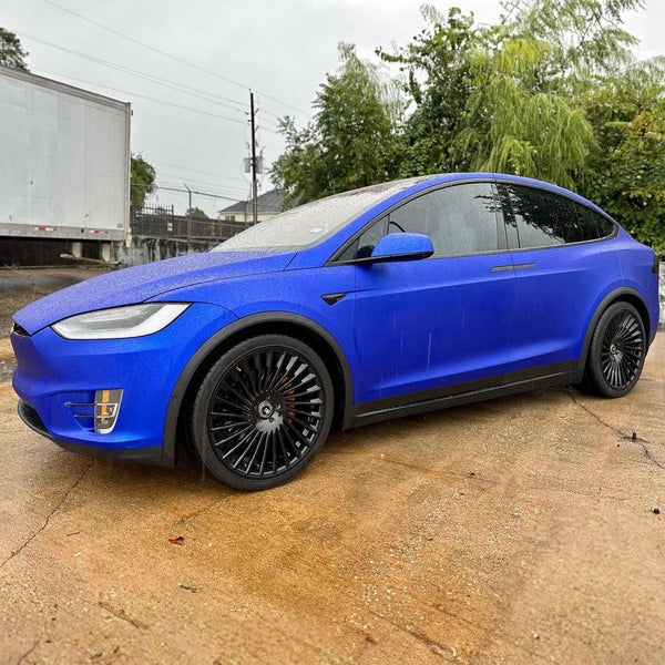 A car wrapped in blue satin vinyl with a protective layer on the hood.