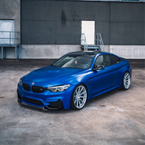 Blue BMW car parked in front of a gray industrial building