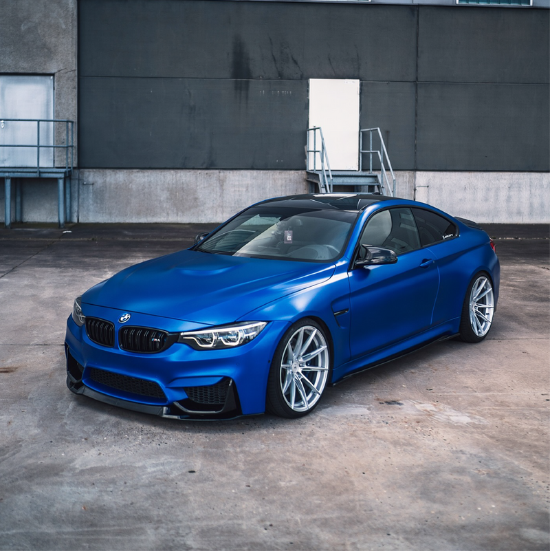 Blue BMW car parked in front of a gray industrial building