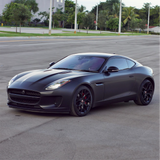 Black sports car on a city street with trees and buildings in the background