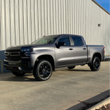 Silver pickup truck parked in front of a metal building