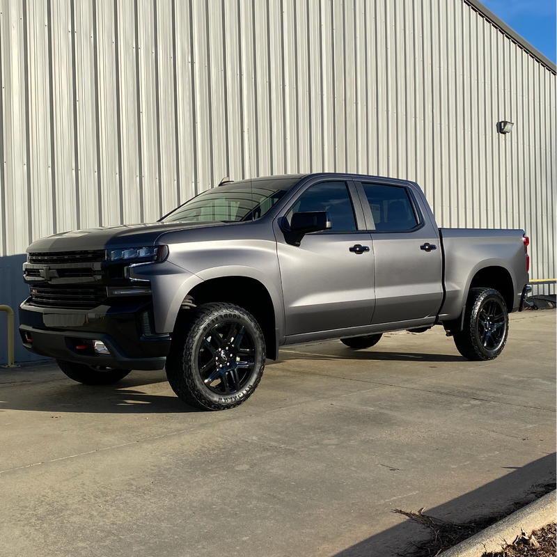 Silver pickup truck parked in front of a metal building