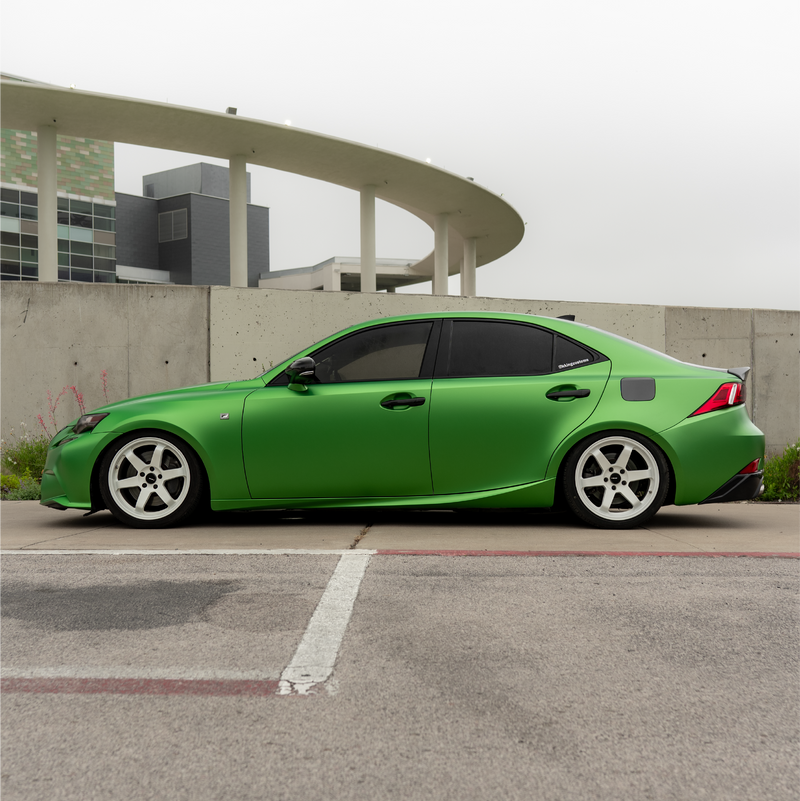 Green car parked in a parking lot with a modern building in the background