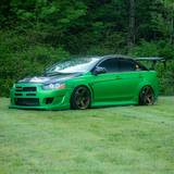 Green sports car on grass with trees in the background