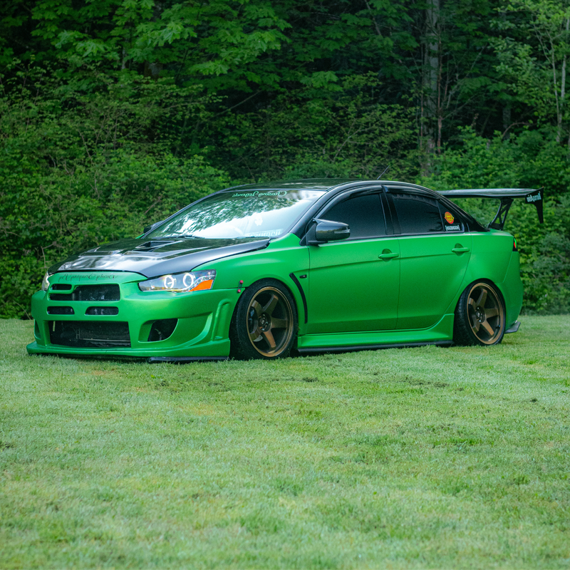 Green sports car on grass with trees in the background