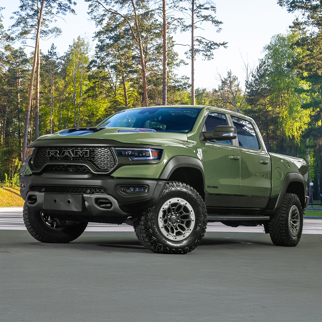 Green Ram truck on a road with trees in the background