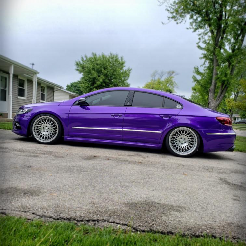 Purple car parked on a driveway with a house and trees in the background