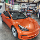 Orange car in a garage with various items and tools in the background