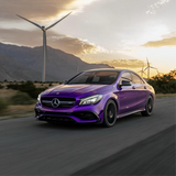 Purple Mercedes-Benz car on a road with wind turbines and mountains in the background