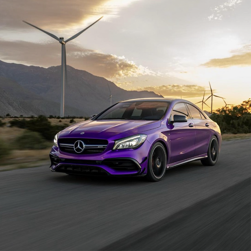 Purple Mercedes-Benz car on a road with wind turbines and mountains in the background